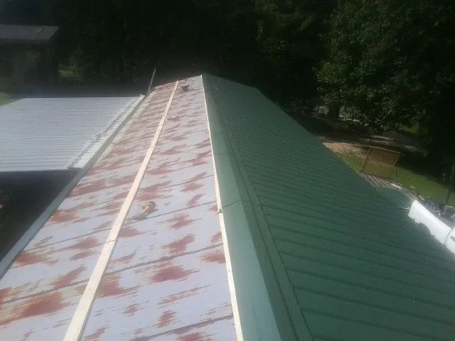 Old rusted panels beside newly installed green metal roofing — Wind Damage Roof Repair by Roofing Brothers in Passaic