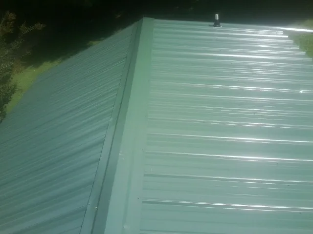 New green metal panels meeting at the ridge of a roof — Flat Roof Repair work by our crew in Passaic