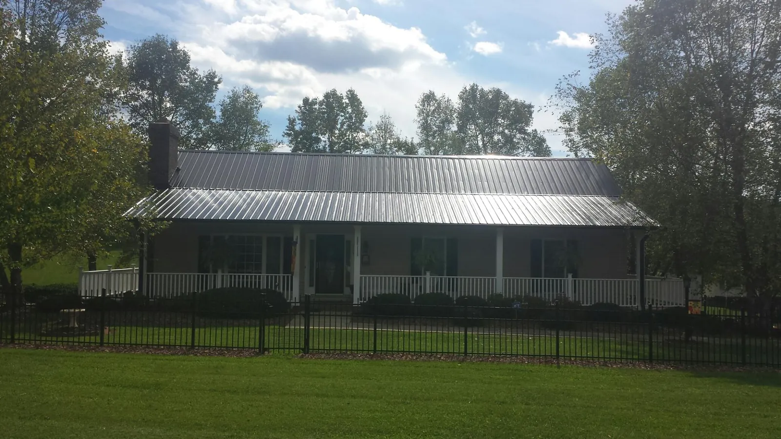 Gray metal roof on a brick ranch with a full width front porch — Gutter Guard Installation work by our crew in Passaic
