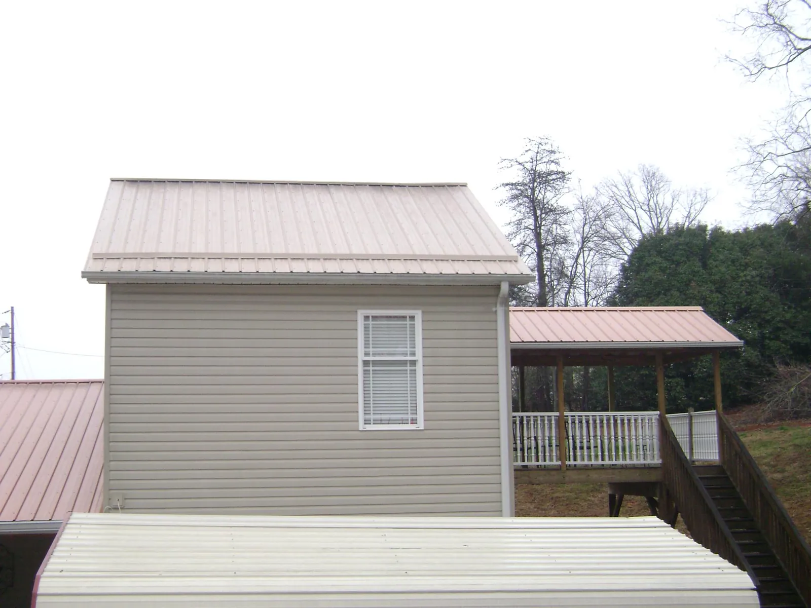 Tan metal roofs on a two story addition and attached porch, from a Roof Replacement job in Passaic