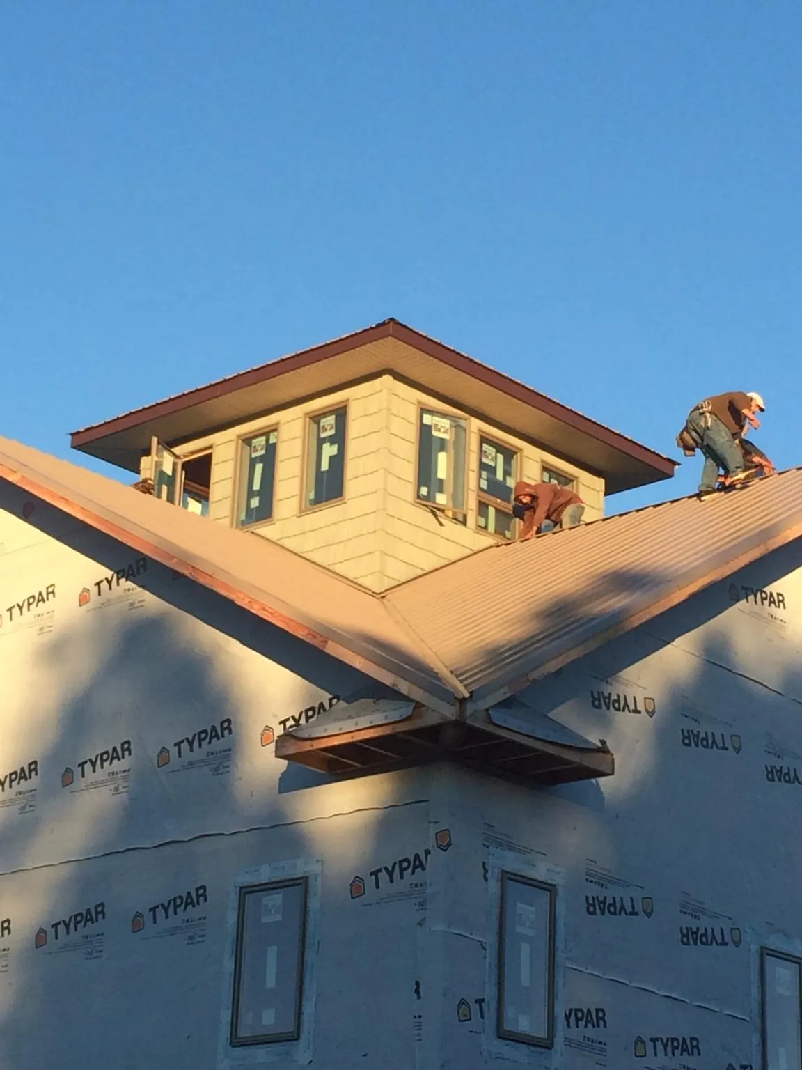Roofers working around a rooftop cupola on a new metal roof at sunset — Roof Waterproofing in Passaic by Roofing Brothers
